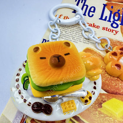 Llavero de arcilla polimérica en miniatura con forma de capibara y sándwich